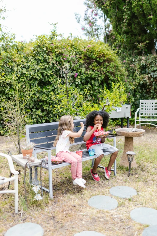 a woman and two children sitting on a bench, lush garden surroundings, furnished with fairy furniture, grey, hero shot