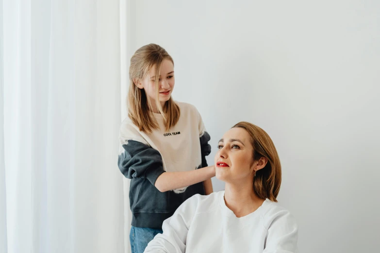 a woman getting her hair done by a hair stylist, by Emma Andijewska, for kids, on a white table, casual pose, broad shoulder