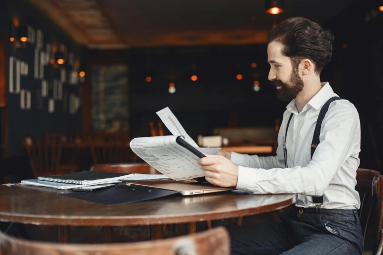 a man sitting at a table reading a newspaper, pexels contest winner, very attractive man with beard, server in the middle, avatar image, profile image