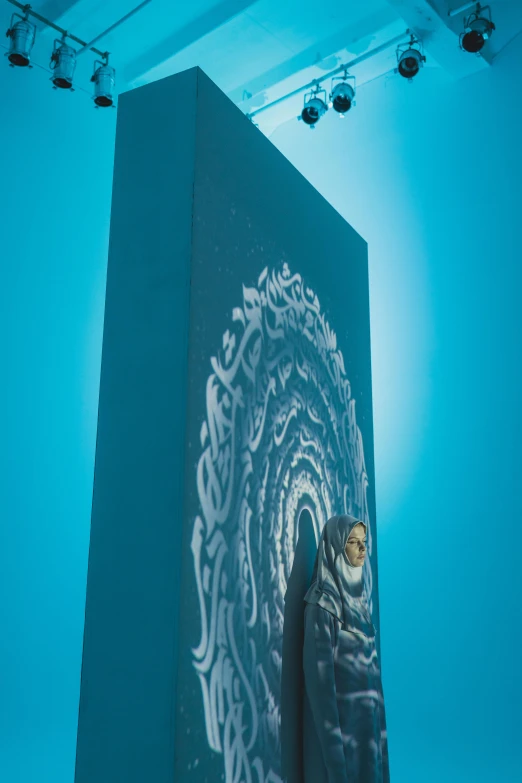 a woman standing in front of a large painting, an airbrush painting, inspired by Ahmed Yacoubi, unsplash contest winner, looking through a portal, relaxed. blue background, lit. 'honored ka'bah'), low-angle shot