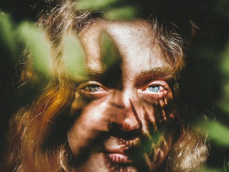 a close up of a person with blue eyes, an album cover, pexels contest winner, covered in plants, faces covered in shadows, color photograph portrait 4k, light glare