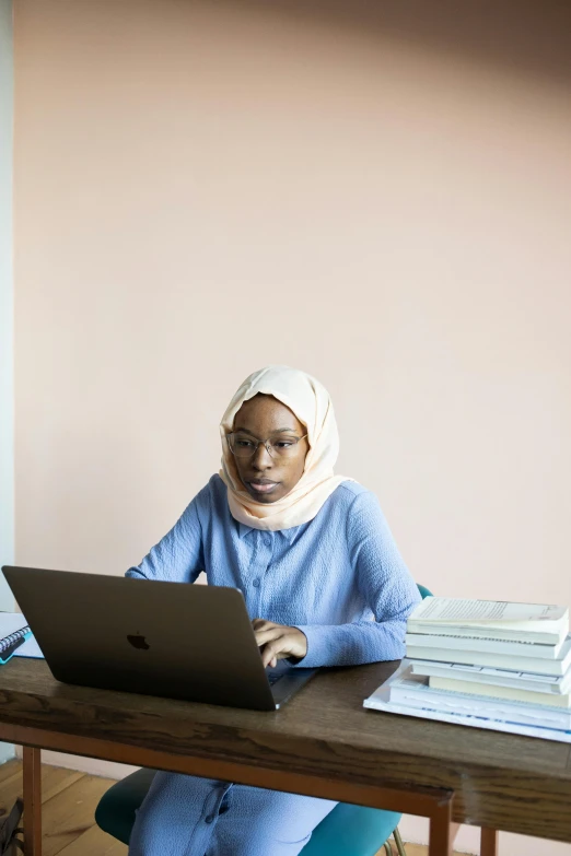 a woman sitting at a desk using a laptop computer, by Arabella Rankin, hurufiyya, riyahd cassiem, stacked image, holding notebook, teaching