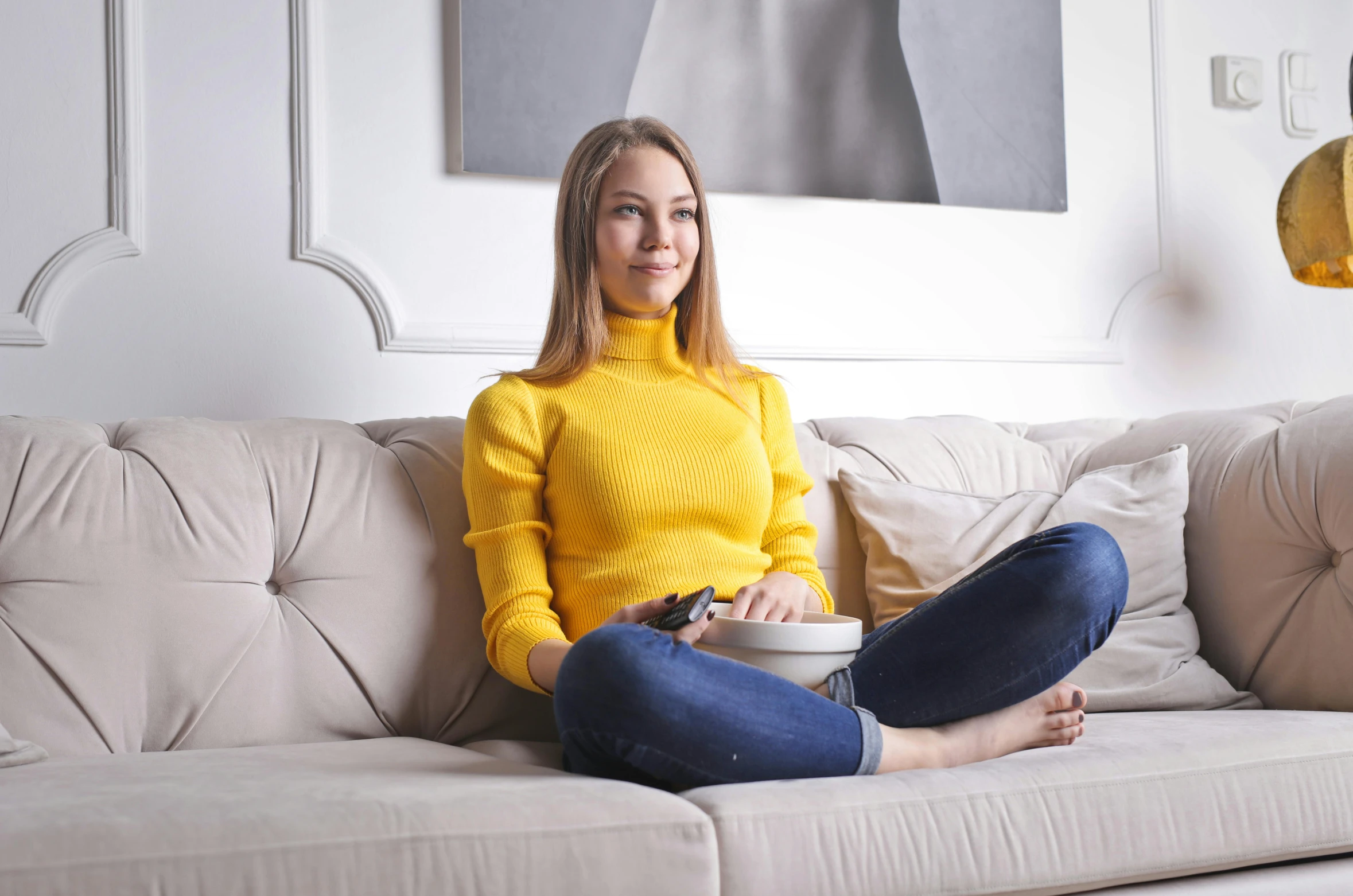 a woman sitting on a couch with a bowl of food, wearing turtleneck, yellow, pokimane, high res photograph