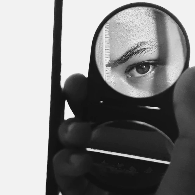 a close up of a person holding a magnifying glass, a black and white photo, by Emma Andijewska, hyperrealism, mirror selfie, 💋 💄 👠 👗, slit pupils, alex miranda