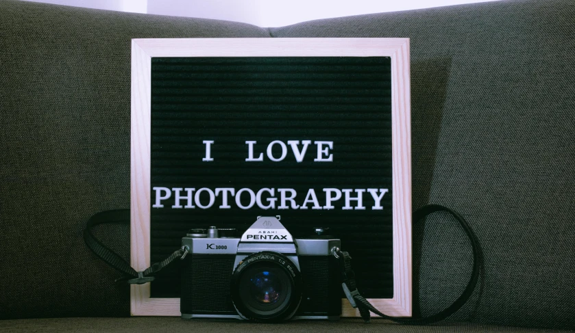 a camera sitting on top of a couch next to a sign that says i love photography, pexels contest winner, low quality photo, portrait photo, paparazzi photo, cinematic outfit photo