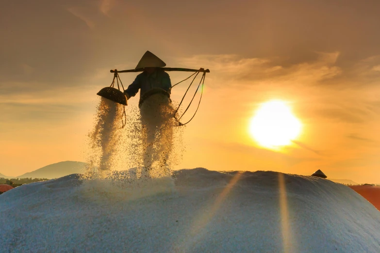 a man standing on top of a pile of snow, inspired by Scarlett Hooft Graafland, pexels contest winner, beautiful raking sunlight, rice, pouring, mining