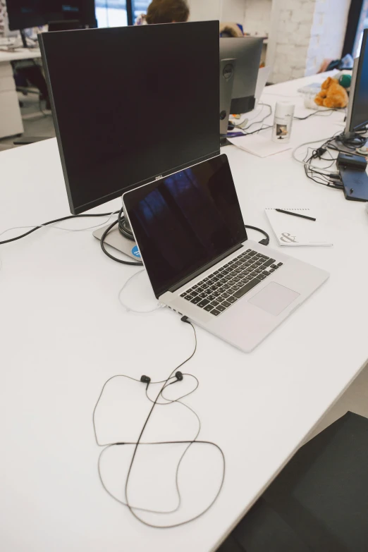 a laptop computer sitting on top of a white desk, by Romain brook, cables out of the ears, multiple desks, captured on iphone, wide long view