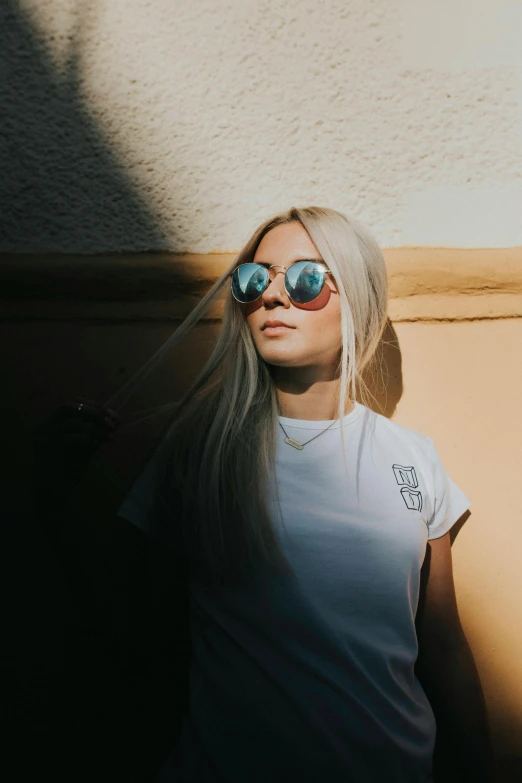 a woman with sunglasses standing in front of a wall, inspired by Elsa Bleda, unsplash contest winner, dressed in a white t-shirt, ava max, discord profile picture, low quality photo