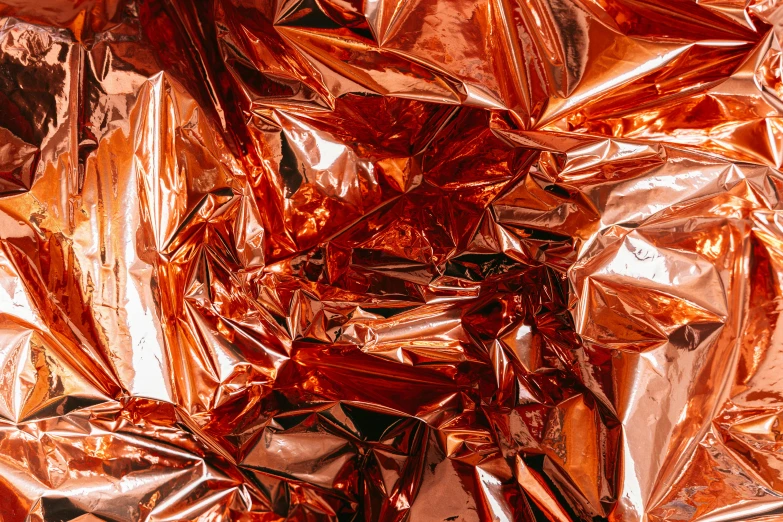 a pile of foil sitting on top of a table, by Julia Pishtar, pexels contest winner, plasticien, dark orange, glossy design, copper, red-fabric