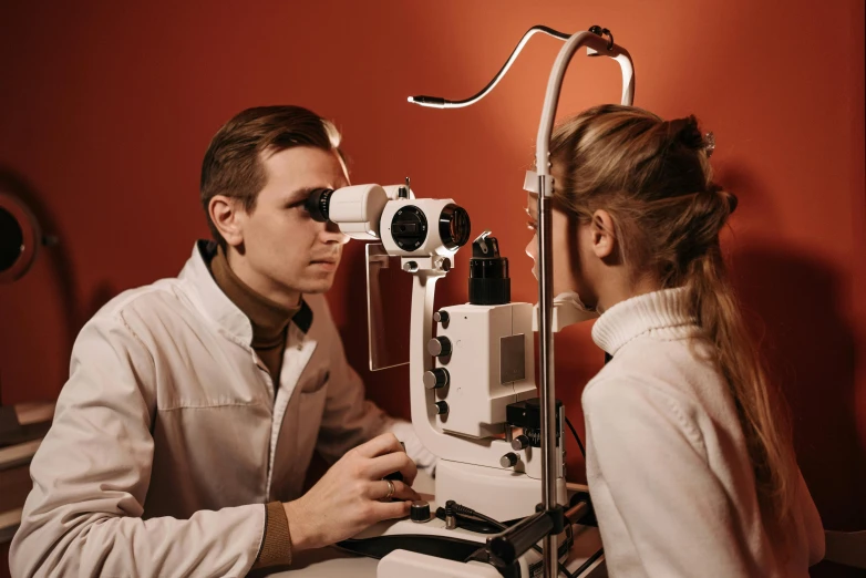 a man and a woman looking through an eye exam machine, by Adam Marczyński, trending on pexels, hyperrealism, one eye red, lane brown, a very macular woman in white, detailed: cornea