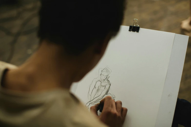 a person drawing a picture on a piece of paper, a drawing, by Adam Marczyński, pexels contest winner, visual art, head and waist potrait, over-shoulder shot, ilustration, beginner art