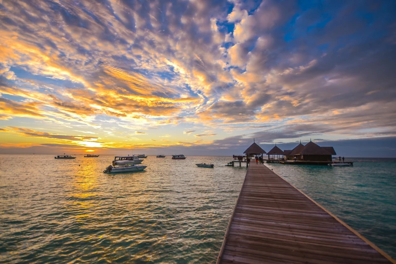 a dock in the middle of a body of water, pexels contest winner, hurufiyya, vibrant sunset, maldives in background, thumbnail, with water and boats