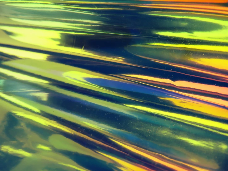 a close up of a surfboard on a body of water, a microscopic photo, inspired by Gabriel Dawe, trending on unsplash, panfuturism, neon-yellow-holographic wings, oil slick, hd footage, plastic texture