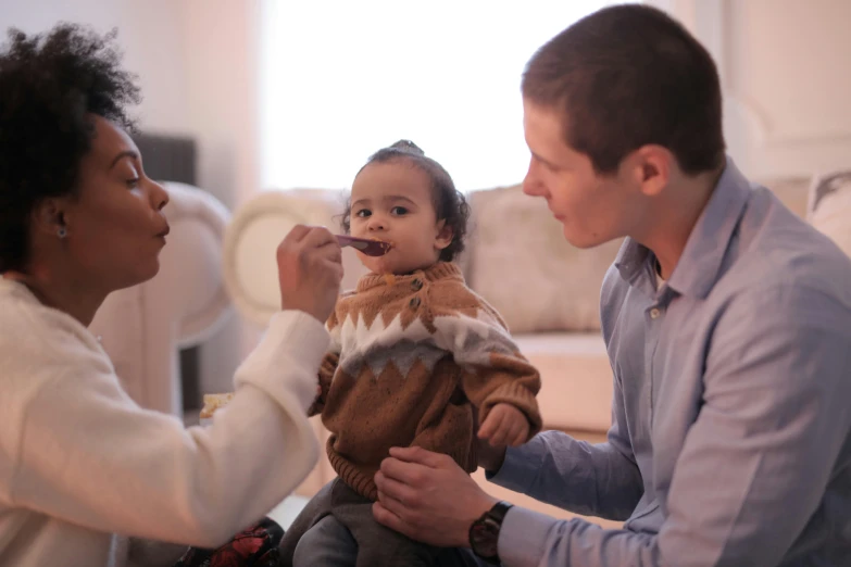 a woman brushing a baby's teeth while sitting on the floor, by Adam Marczyński, pexels contest winner, symbolism, drinking cough syrup, portrait of family of three, with a stethoscope, mixed race