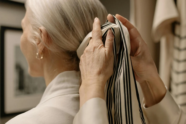 a close up of a person holding a towel, silver hair (ponytail), an old lady, off - white collection, ribbon in her hair