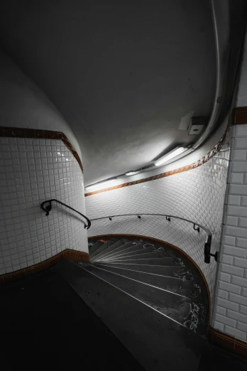 a black and white photo of a spiral staircase, inspired by Brassaï, unsplash, art nouveau, subway station, tiles, 8k. volumetric lighting, late evening