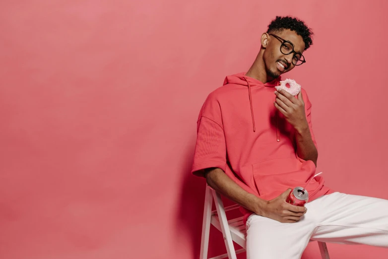 a man sitting on a chair eating a donut, an album cover, inspired by Ismail Gulgee, trending on pexels, red sport clothing, drinking a strawberry iced latte, pink, profile photo