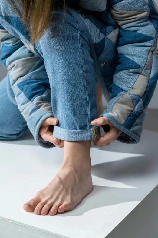 a woman sitting on top of a white box, by Nina Hamnett, trending on pexels, hyperrealism, wearing a jeans jackets, foot wraps, hibernation capsule close-up, trending on dezeen