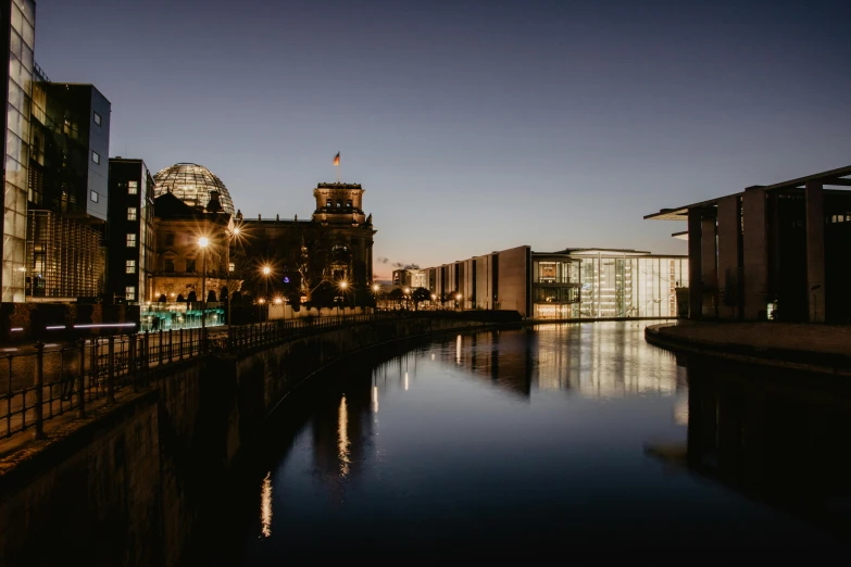 a river running through a city next to tall buildings, pexels contest winner, berlin secession, calm evening, inside berghain, mies van der rohe, nighttime scene