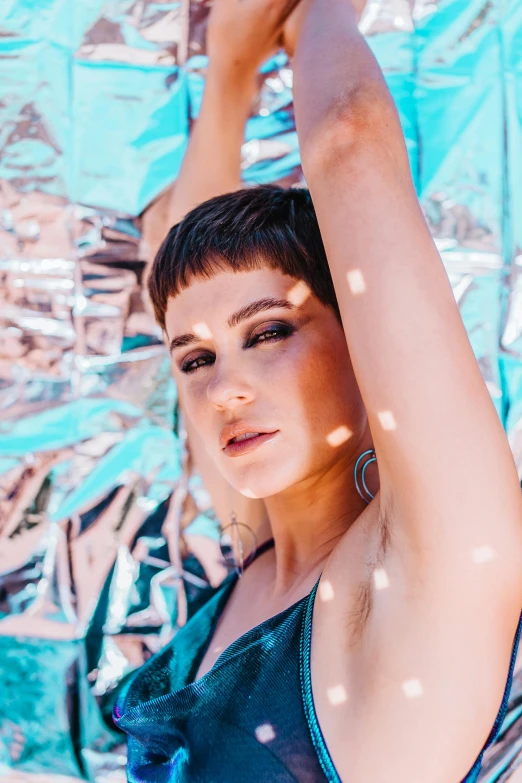 a woman in a blue dress holding an umbrella, an album cover, inspired by Elsa Bleda, trending on pexels, holography, blue short hair, intense sunlight, metallic cyan bodysuit, 35mm photo