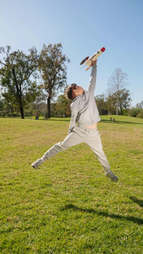 a man jumping in the air to catch a frisbee, an album cover, unsplash, wearing a track suit, stretching her legs on the grass, gray, 15081959 21121991 01012000 4k