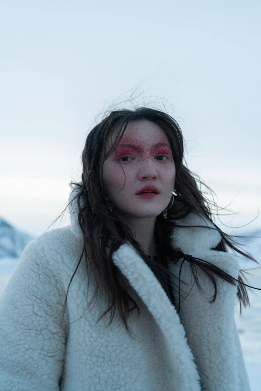 a woman standing on top of a snow covered field, an album cover, inspired by Kim Tschang Yeul, trending on pexels, heavy makeup, inuit, grimes, close up portrait shot