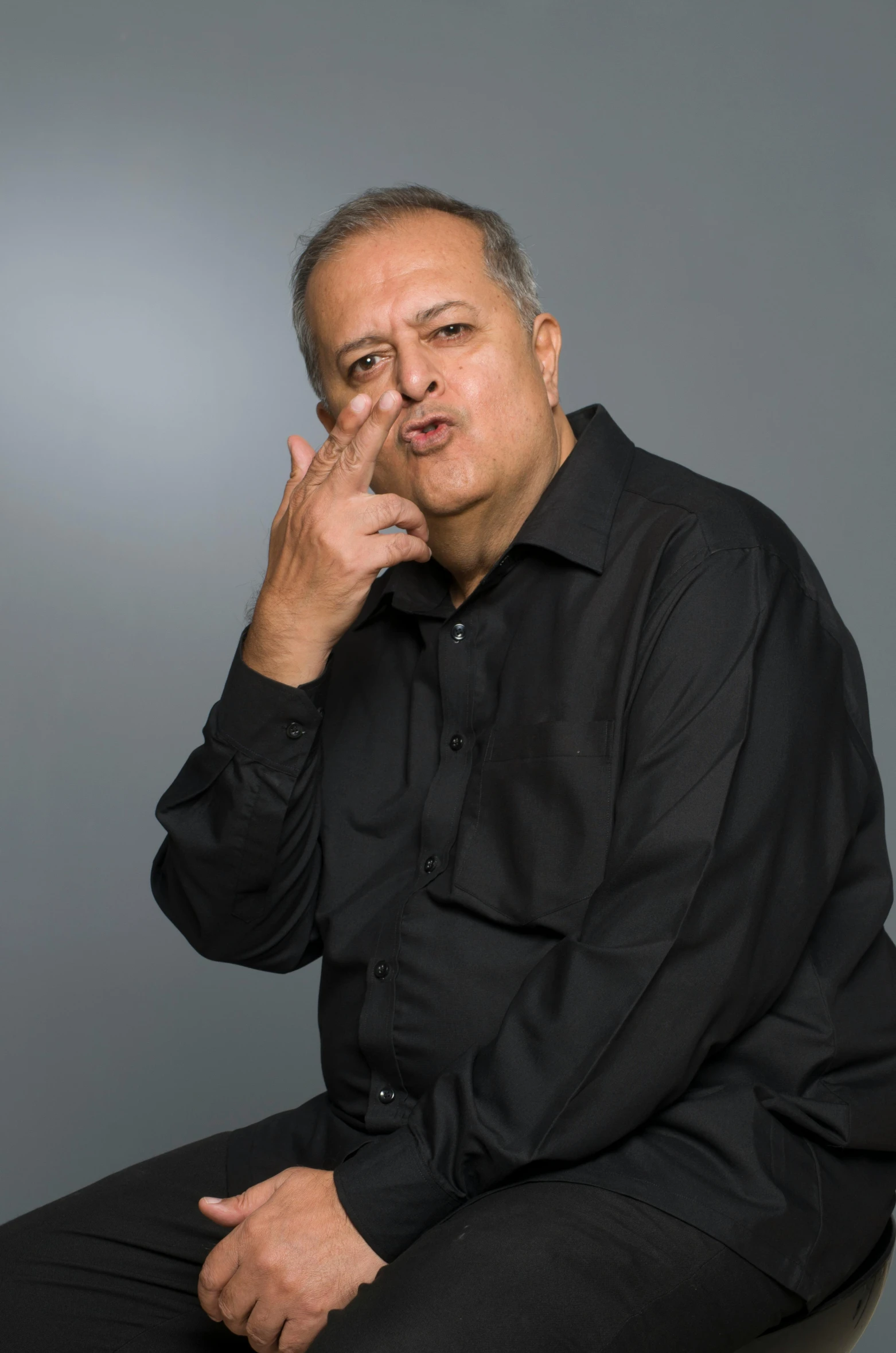 a man in a black shirt sitting on a stool, an album cover, inspired by Mahmoud Farshchian, pointing index finger, stern expression, on clear background, no crop