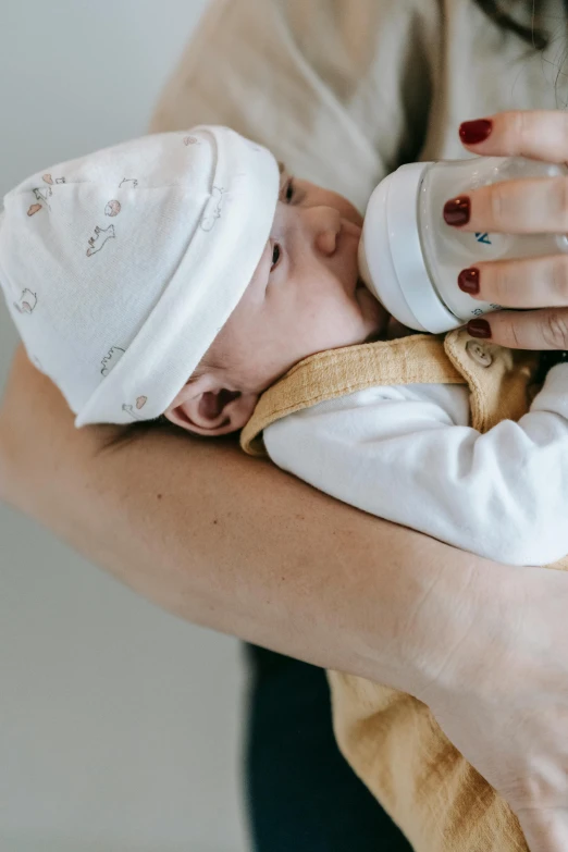 a woman feeding a baby with a bottle, by Carey Morris, pexels contest winner, symbolism, white, hugging, brown, lachlan bailey