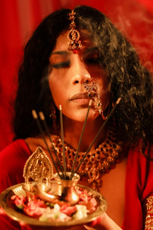 a woman in a red dress holding a plate of food, an album cover, trending on pexels, hurufiyya, incense, cinematic goddess close shot, provocative indian, ( ( theatrical ) )