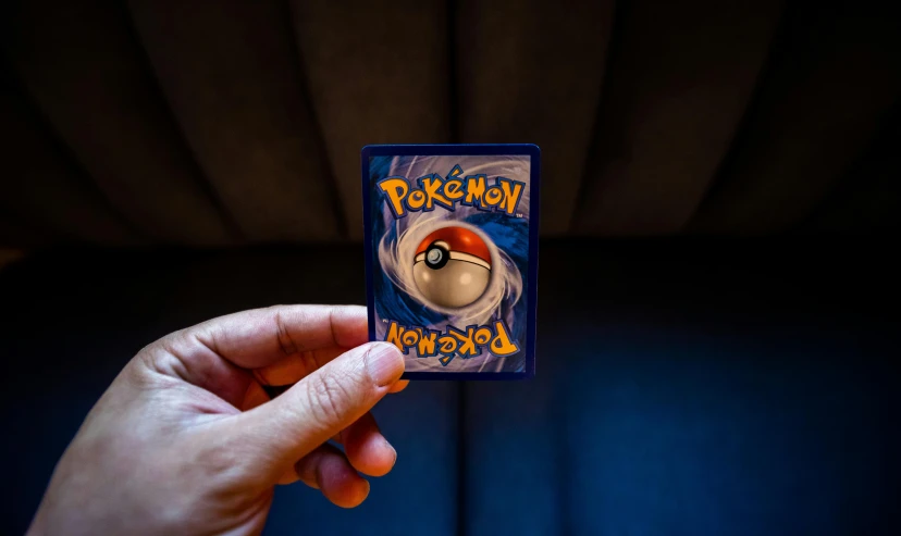 a person holding a pokemon card in their hand, inspired by Ken Sugimori, pexels contest winner, futuristic nft card game, trading card front, 2000s photo, pokeball