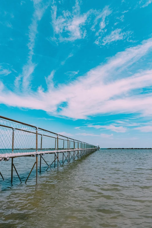 a pier in the middle of a body of water, leading to the sky, netting, clear blue skies, instagram post