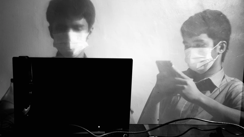 a man sitting in front of a laptop computer, a black and white photo, by Emma Andijewska, computer art, people are wearing masks, mirror selfie, during sandstorm, pc screen image