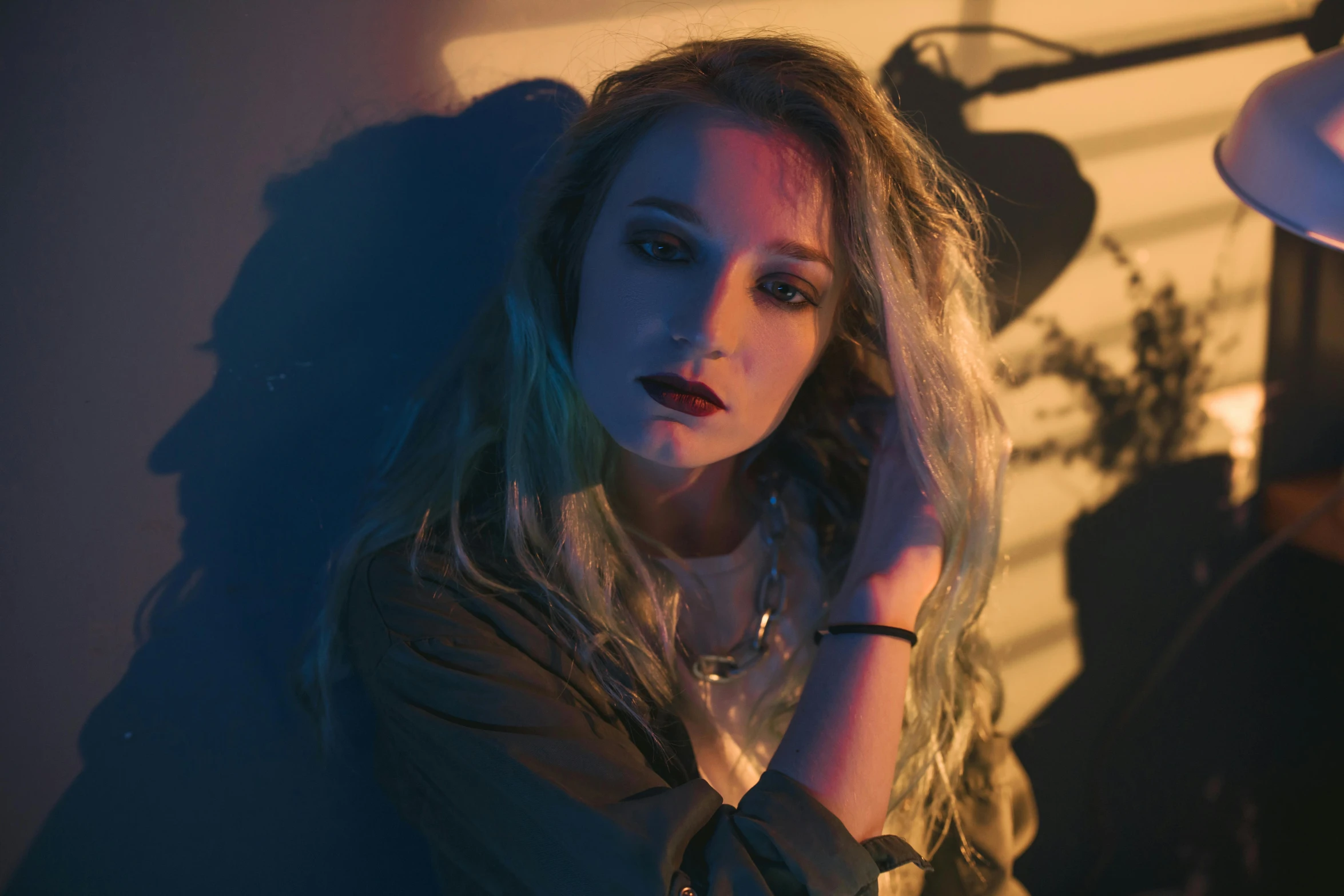 a woman with long hair sitting in front of a lamp, inspired by Elsa Bleda, pexels contest winner, portrait of kim petras, grungy woman, low - lighting, music video