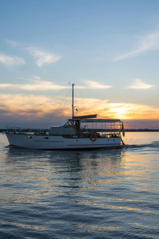 a white boat floating on top of a body of water, at the sunset, on a boat, water surrounds the ship