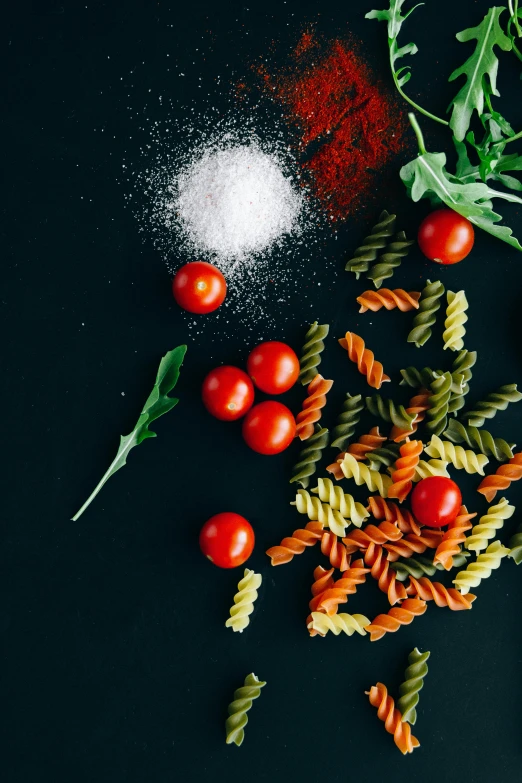 various types of pasta on a black surface, pexels contest winner, green and red plants, bold complementary colours, university, dark kitchen