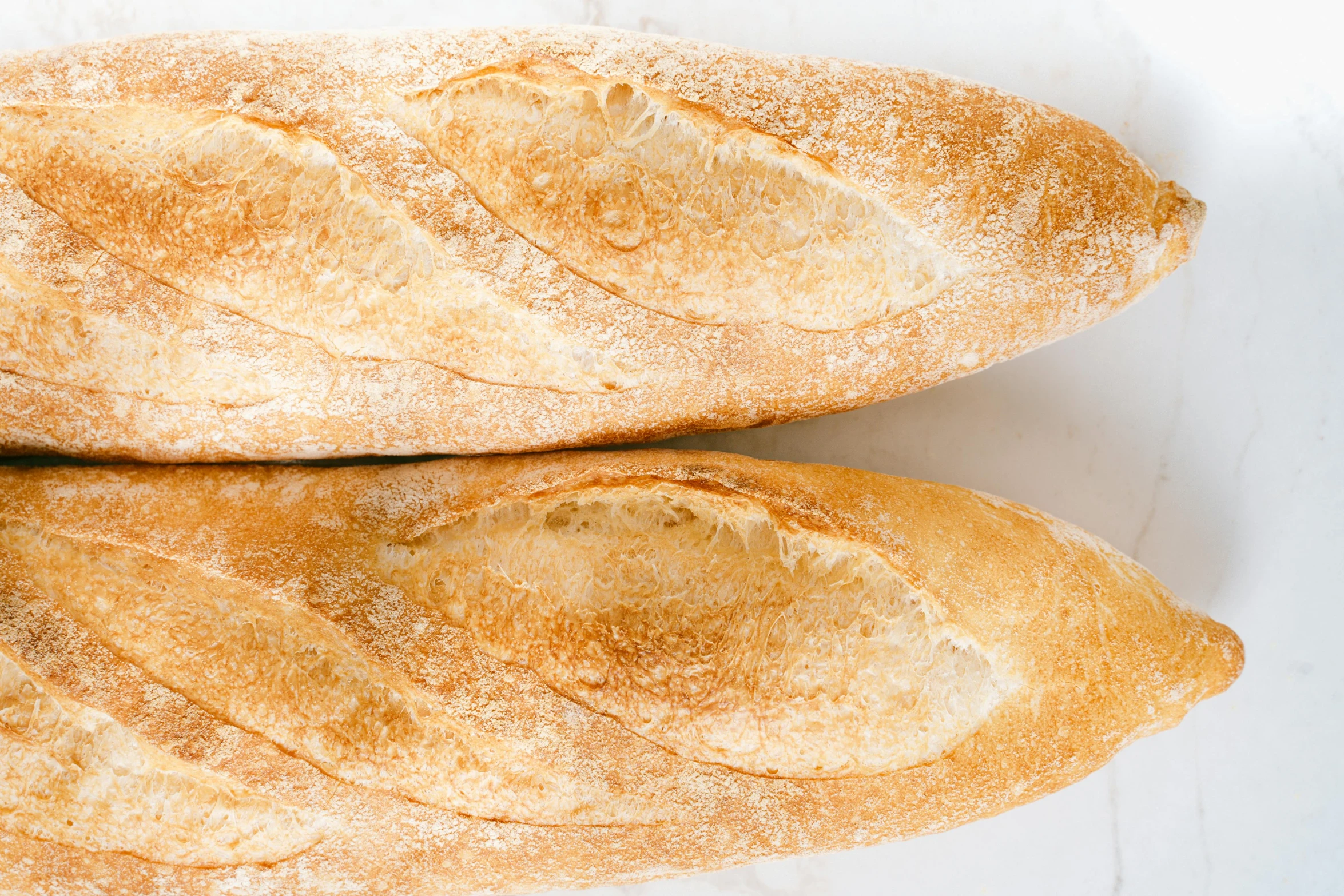 two loaves sitting next to each other on a table, trending on pexels, background image, baking french baguette, birdseye view, white