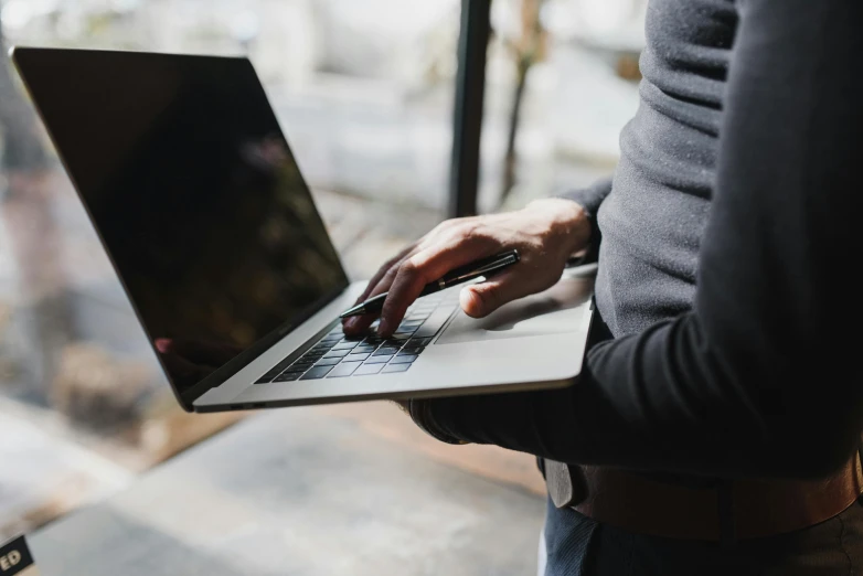 a close up of a person holding a laptop, by Carey Morris, pexels, panels, standing, easy to use, background image