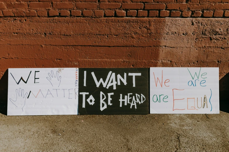 a couple of signs that are on the side of a building, a poster, by Carey Morris, trending on unsplash, protest, three heads, on sidewalk, schools