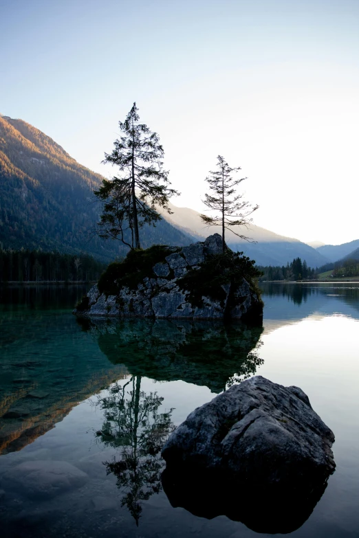 a large rock sitting in the middle of a lake, by Karl Walser, in the mountains, at dawn, green waters, low iso