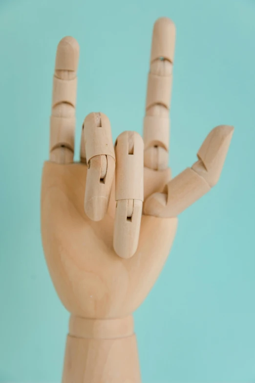 a wooden hand making a peace sign on a blue background, a surrealist sculpture, inspired by Sarah Lucas, trending on pexels, ball jointed doll, tall thin, how to, image