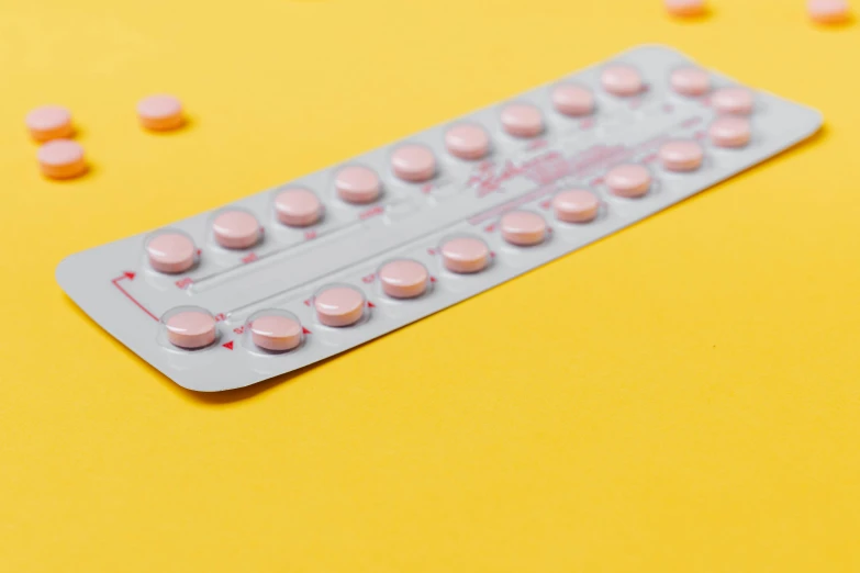 pink pills in a blister pack on a yellow background, by Rachel Reckitt, trending on pexels, sitting on a table, panels, on grey background, studs
