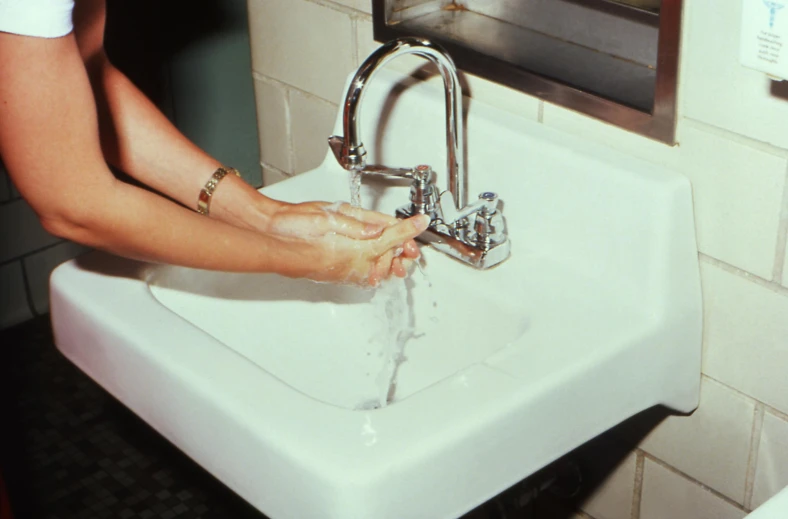 a person washing their hands in a sink, by Pamela Ascherson, 1980s photograph, healthcare, splash image, joel meyerowitz