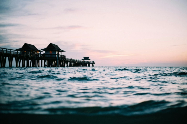 a pier in the middle of a body of water, pexels contest winner, huts, faded glow, a photo of the ocean, cute photo