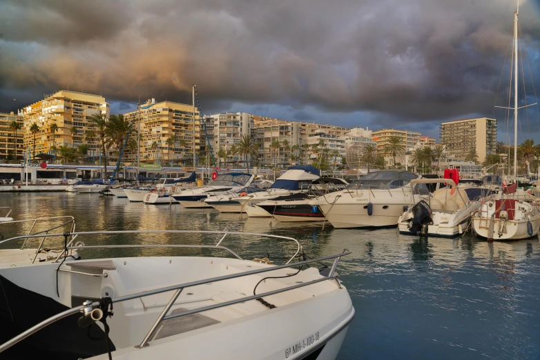 a harbor filled with lots of boats under a cloudy sky, by Simon Marmion, pexels contest winner, marbella, grey cloudy skies, manly, warm glow