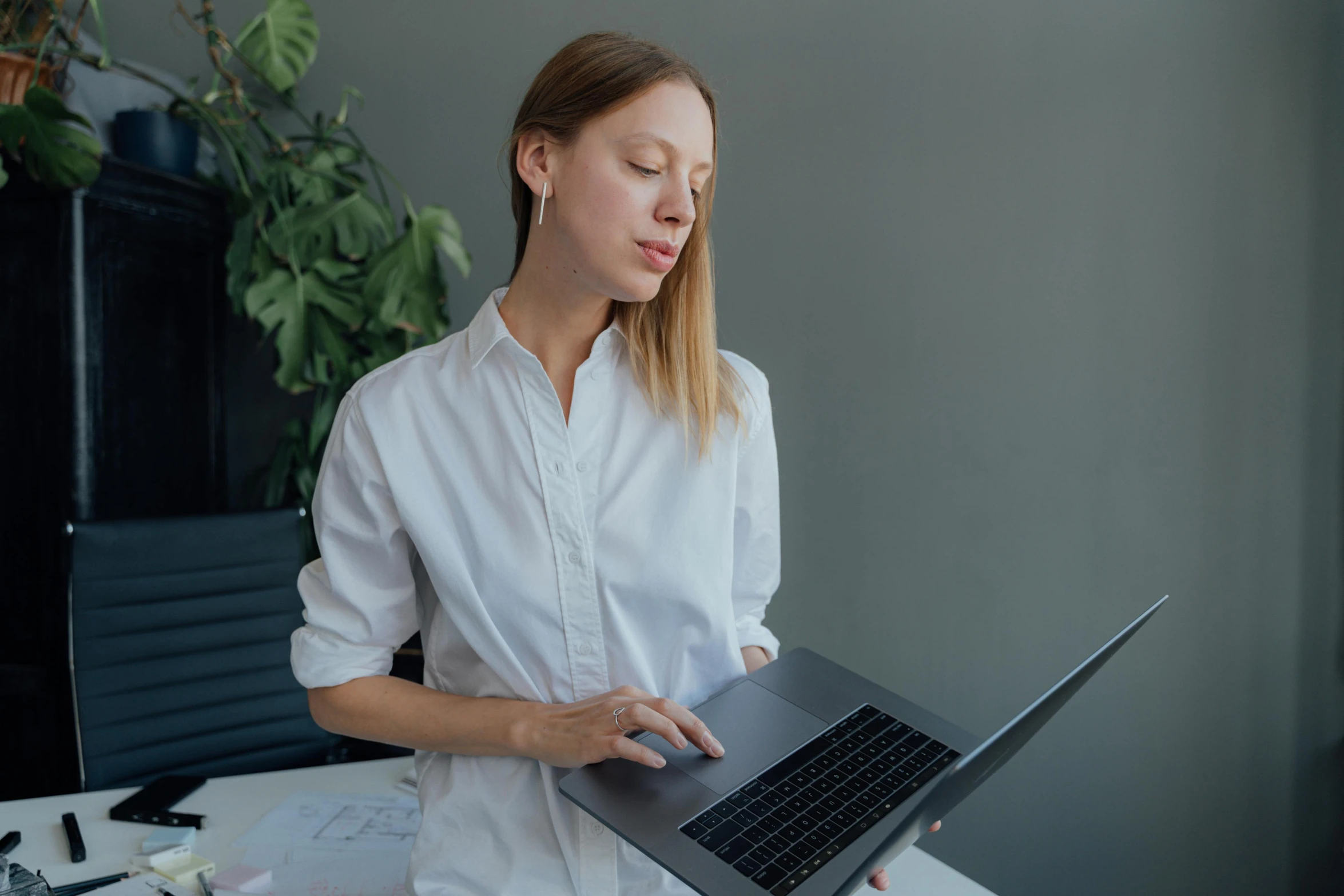 a woman in a white shirt is holding a laptop, pexels contest winner, avatar image, bent - over posture, low quality photo, ad image