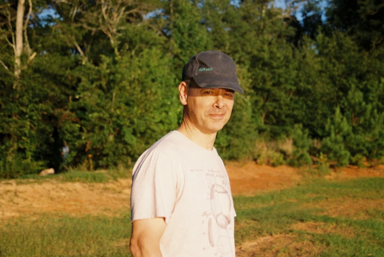 a man standing in a field with a frisbee, an album cover, by Andrew Stevovich, wearing a baseball cap, ignant, john carmack, profile image