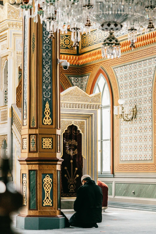 a person sitting in a room with a chandelier hanging from the ceiling, inspired by Osman Hamdi Bey, trending on unsplash, hurufiyya, mosque synagogue interior, 2 5 6 x 2 5 6 pixels, kneeling, ornate patterned people