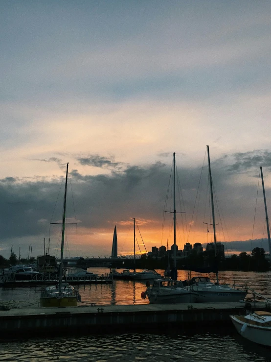 a harbor filled with lots of boats under a cloudy sky, a picture, pexels contest winner, city sunset, photo on iphone, warm summer nights, grey