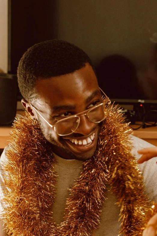 a man wearing a gold tinsel around his neck, trending on pexels, happening, brown skin man with a giant grin, nerdy, chilly, digital still