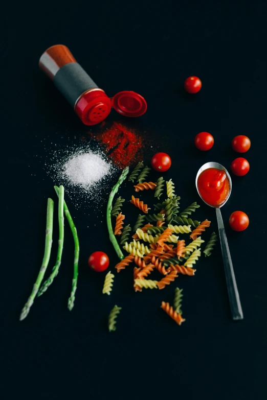a table topped with lots of different types of food, a still life, by Andries Stock, pexels contest winner, red on black, pasta, salt shaker, veggies